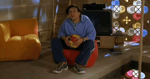 a man is sitting on a bean bag chair holding a soccer ball