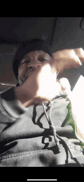 a man wearing a black hat and a grey hoodie with the letter g on it