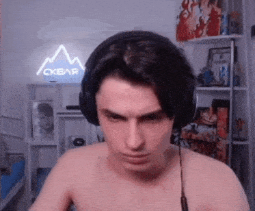 a shirtless man wearing headphones in front of a neon sign that says ' ckbar '