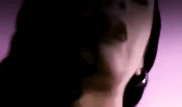 a close up of a woman 's face in a dark room with a purple background .