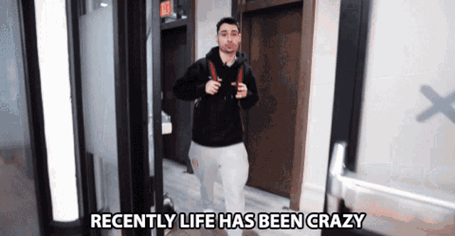 a man with a backpack walks down a hallway with the words recently life has been crazy above him