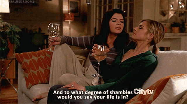 two women sitting on a couch drinking wine with the words and to what degree of shambles citytv written on the bottom of the screen