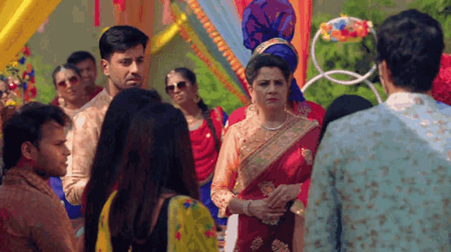 a woman in a red saree stands in front of a group of people