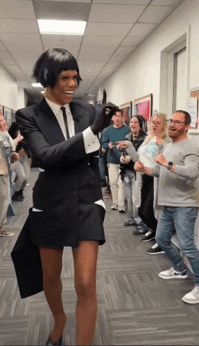 a woman in a suit is standing in a hallway with people