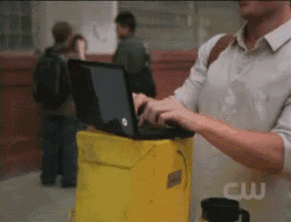 a man is using a laptop on top of a yellow bucket with the cw logo on it