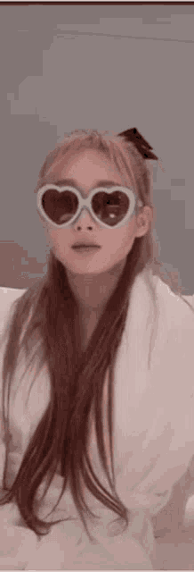 a woman wearing heart shaped sunglasses and a white towel .