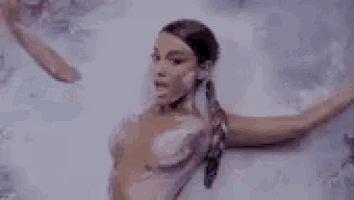 ariana grande is standing in front of a painting of a woman .