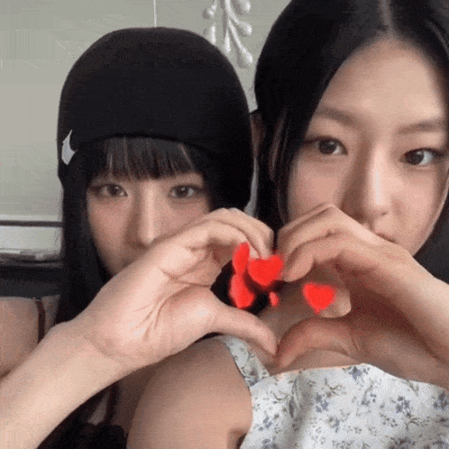 a woman wearing a nike hat makes a heart shape with her hands