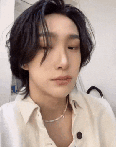 a close up of a person wearing a white shirt and a pearl necklace .