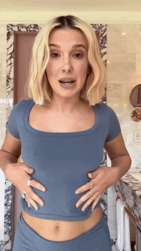 a woman in a blue shirt is holding her stomach