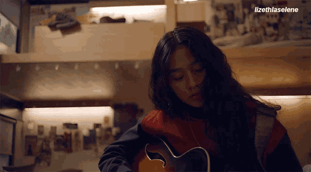 a woman playing a guitar with lizethlaselene written on the bottom right