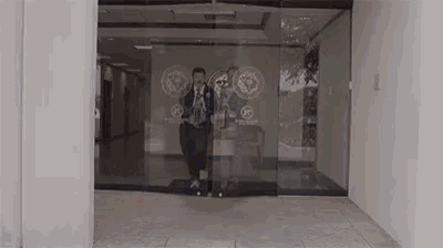a man is walking through a glass door in a building .