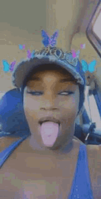 a woman wearing a hat is sticking her tongue out while sitting in a car .