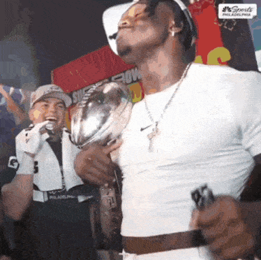 a man in a white shirt is holding a trophy with the word sports on it