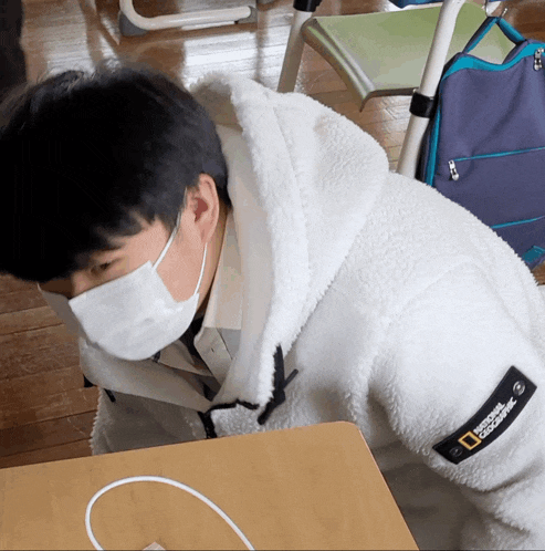 a man wearing a national geographic jacket laying on the floor