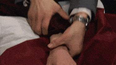 a man wearing a watch is holding another man 's hand