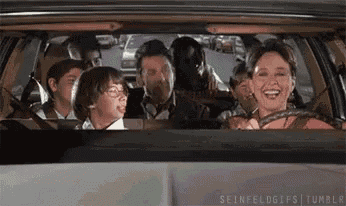a woman is driving a car with a group of people sitting in the back seat .