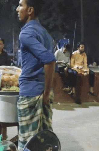 a man in a blue shirt is standing in front of a table with food
