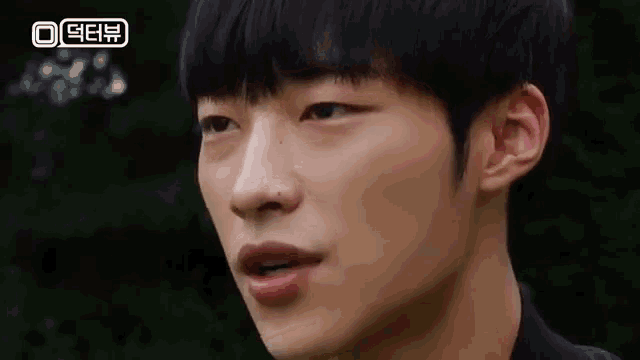 a close up of a young man 's face with his mouth open and a green background .