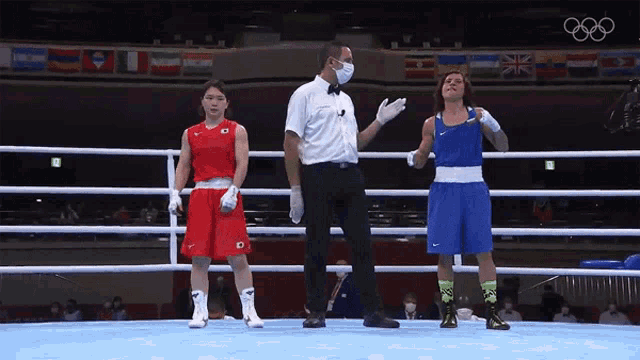 a referee wearing a mask stands in a boxing ring with two boxers