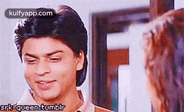 a man and a woman are looking at each other in a room and smiling .