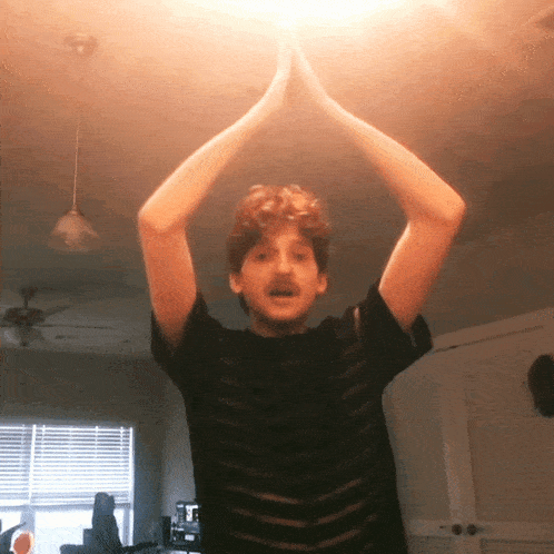 a man in a black striped shirt is raising his arms in the air