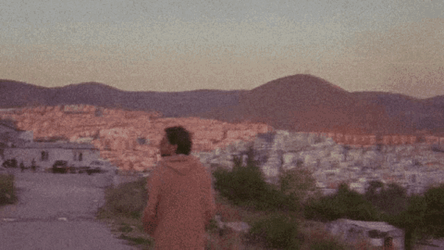 a man in a brown jacket stands in front of a city