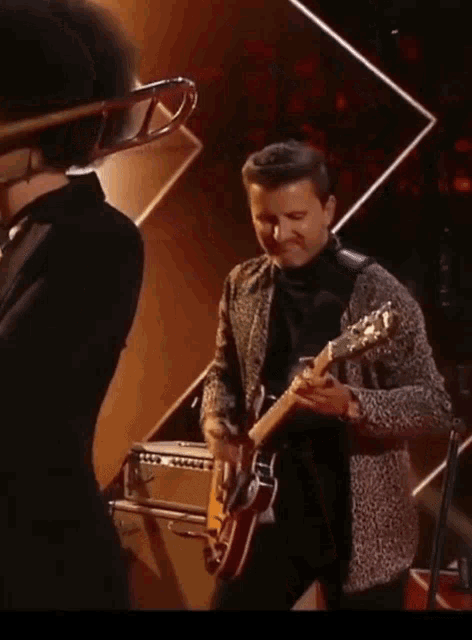a man in a leopard print jacket is playing an electric guitar