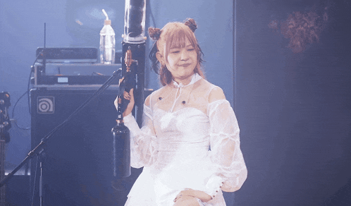 a woman in a white dress holds a microphone
