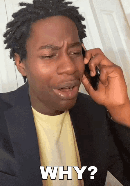 a man in a suit is talking on a cell phone and has the word why written on his face