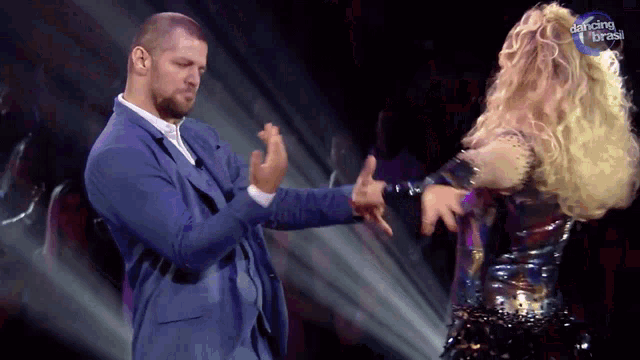 a man in a blue suit is dancing with a woman in a dancing brasil outfit