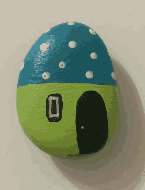 a green and blue rock with polka dots and a black door