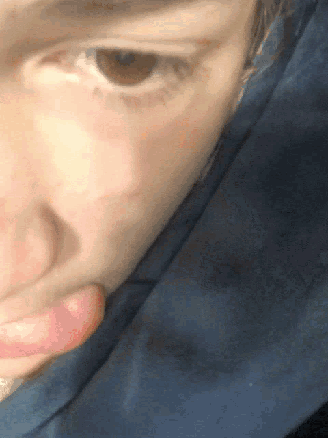 a close up of a person 's face with a blue blanket behind them