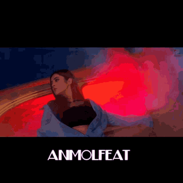 a woman in a blue jacket is standing in front of a red light with the words anmolfeat written below her