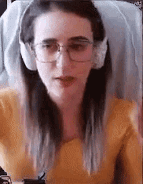 a young woman wearing glasses and headphones is sitting in a chair .