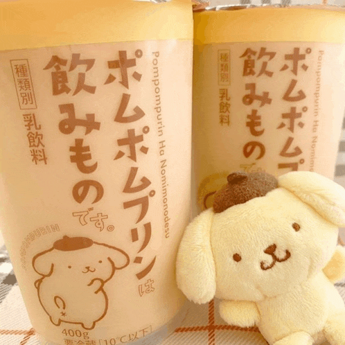 a stuffed animal is sitting next to a cup of pompompurin