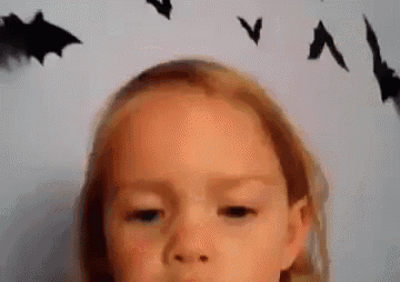 a little girl is making a face in front of a wall with bats on it .