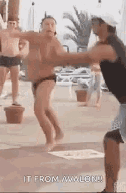 a man in a bathing suit is dancing in a pool with other men .
