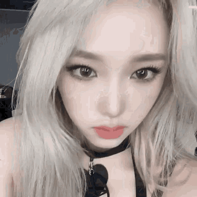 a close up of a woman with blonde hair wearing a choker .