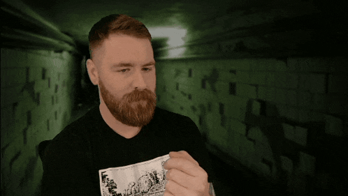 a man with a beard is wearing a black shirt that says " what "