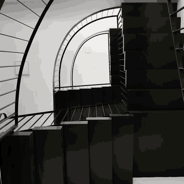 a black and white photo of a spiral staircase with a metal railing