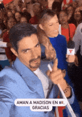 a man is holding a microphone in front of a crowd and says aman a madison en gracias .