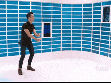 a man in a black shirt is dancing in front of a wall with blue stripes