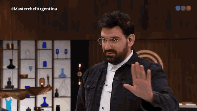 a man wearing glasses says es ley in a kitchen