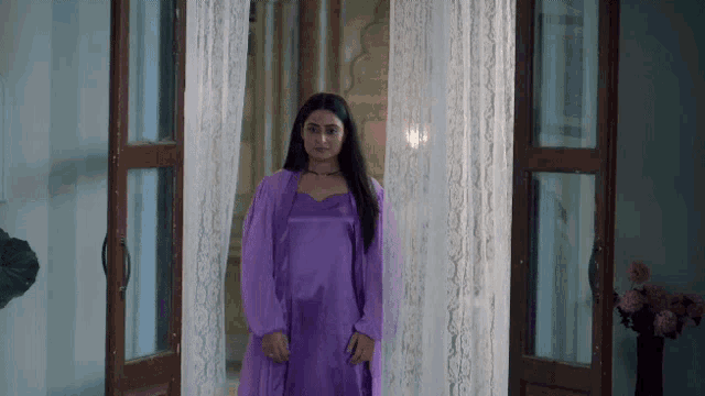 a woman in a purple dress stands in front of a door