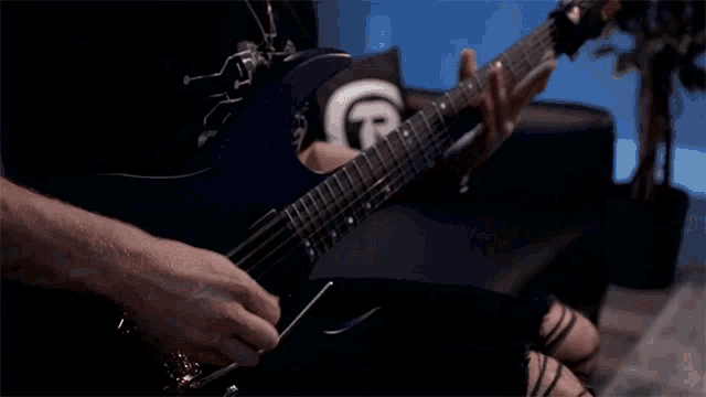 a man is playing an electric guitar with a white t on his shirt