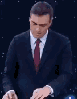 a man in a suit and tie is standing in front of a black background .