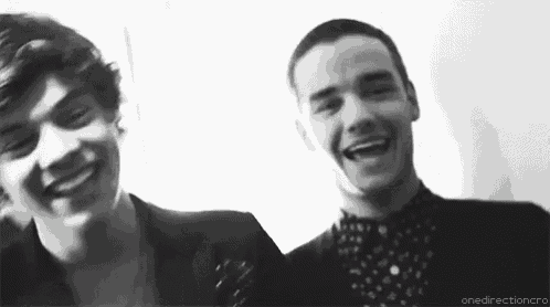 a black and white photo of two young men laughing and smiling .