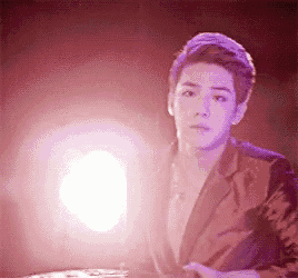 a young man in a suit is standing in front of a bright light