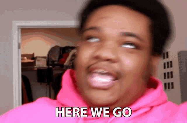 a man wearing a pink hoodie is saying here we go